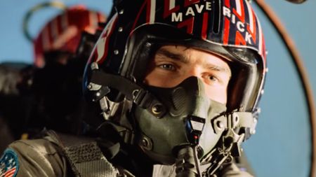 Tom Cruise as Maverick in Top Gun flying and wearing a helment that says "Maverick." 