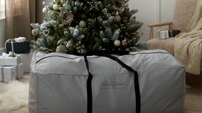The White Company Tree Storage Bag in grey in front of Christmas tree 