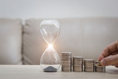 Hourglass next to stacks of coins