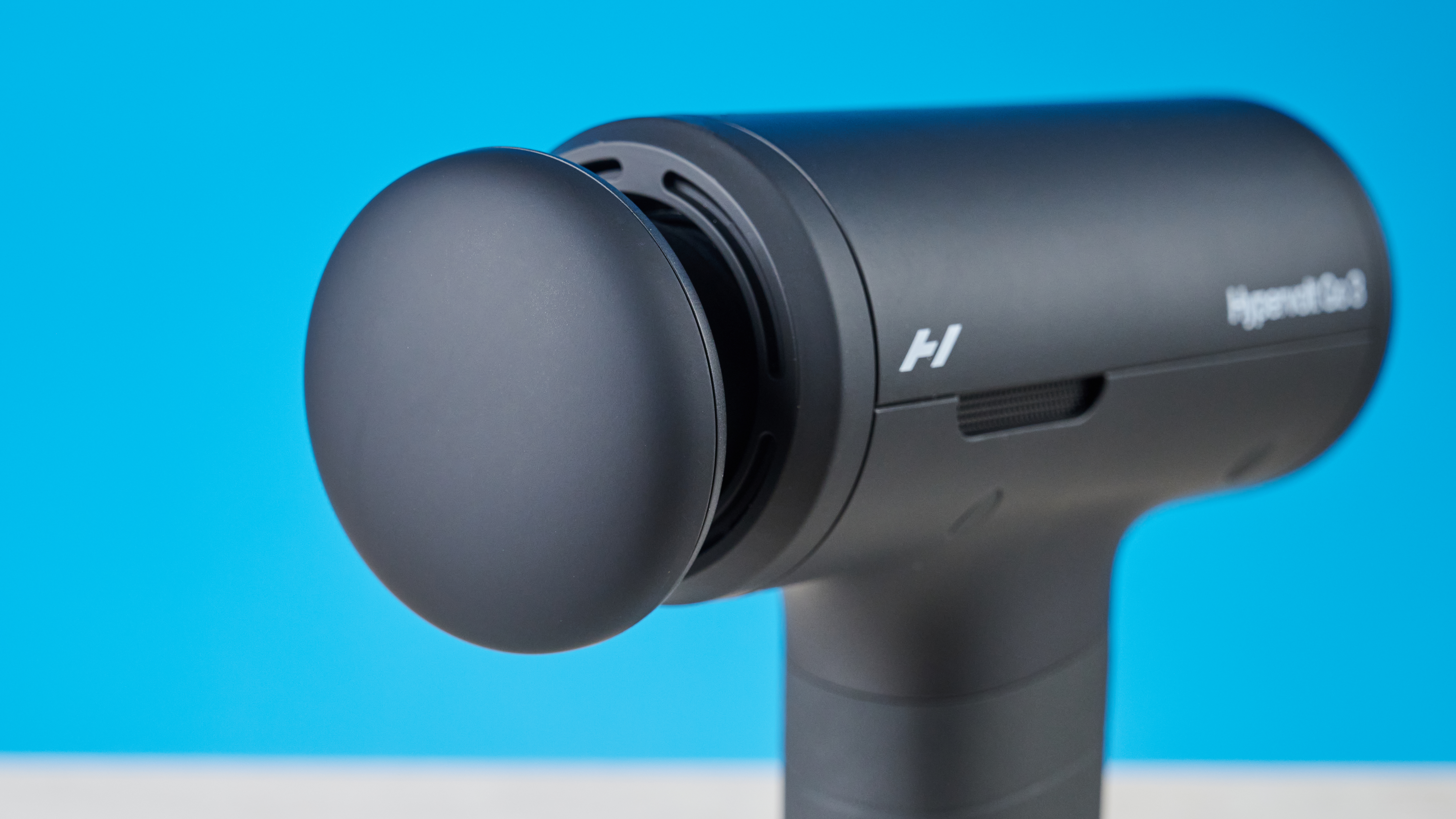 Hyperice Hypervolt Go 3 massage gun photographed in front of a blue background