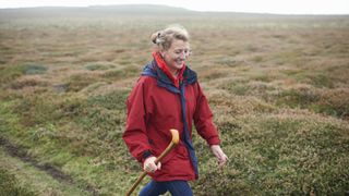 A woman hiking in the moors with a staff