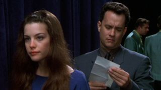 Tom Hanks reads a letter while standing behind Liv Tyler in That Thing You Do!