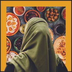 A woman wearing a headscarf looking at food as seen from behind.