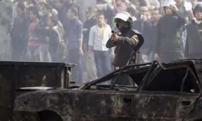 A policeman fires a shotgun with rubber bullets at protesters during clashes in Tahrir Square: Egyptians continue to demand that the country's military leaders hand over power to civilians.