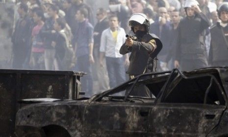 A policeman fires a shotgun with rubber bullets at protesters during clashes in Tahrir Square: Egyptians continue to demand that the country&amp;#039;s military leaders hand over power to civilians.