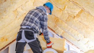 man using mineral wool to insulate loft