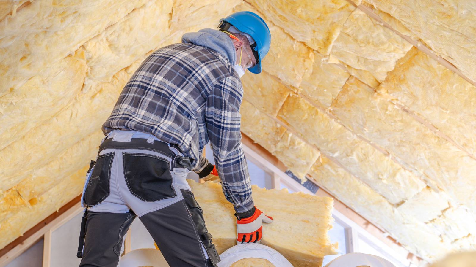 man using mineral wool to insulate loft