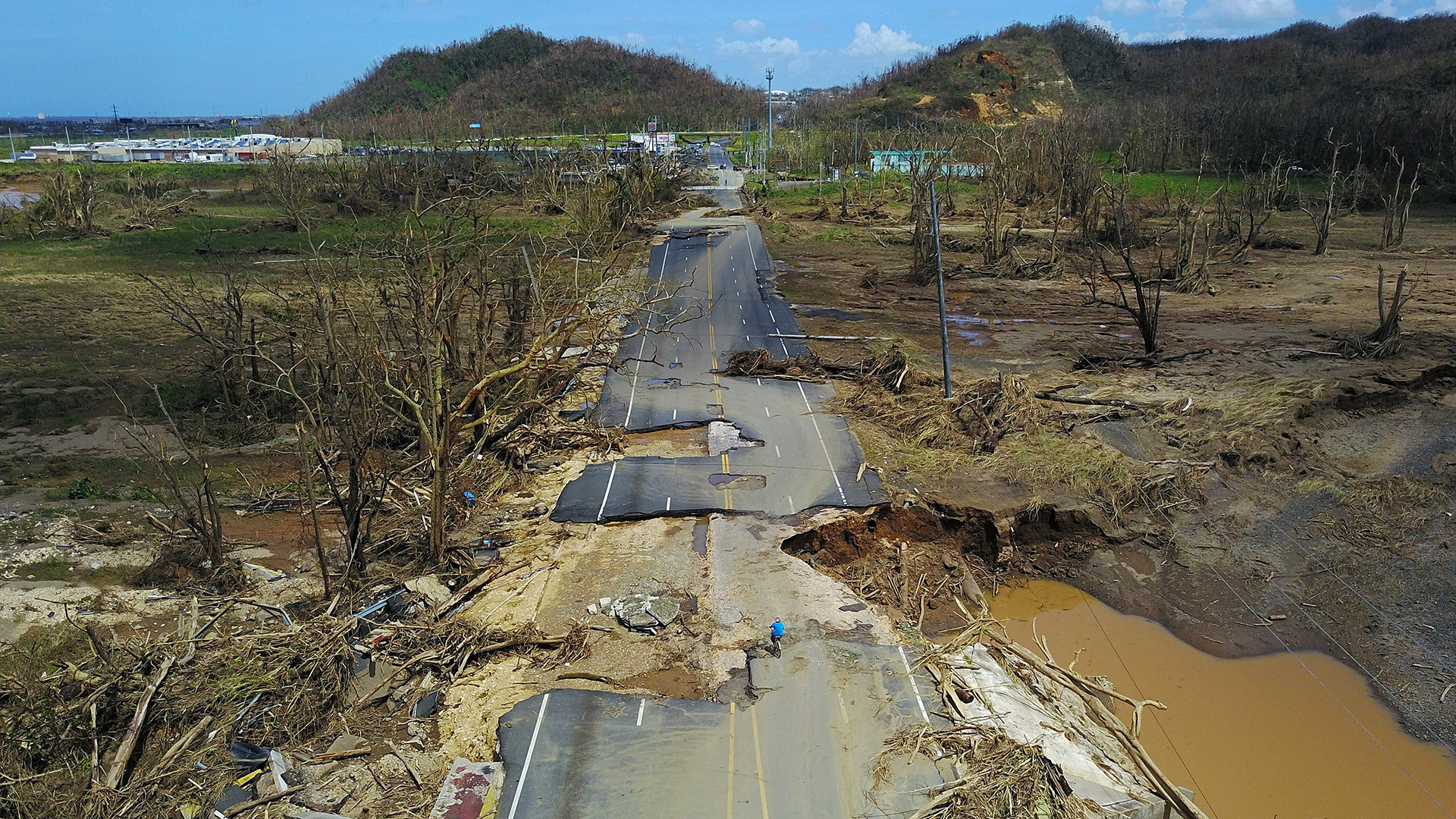 A man rides a bicycle through a damaged road in Toa Alta, west of San Juan, Puerto Rico, on Sept. 24, 2017, after the passage of Hurricane Maria.