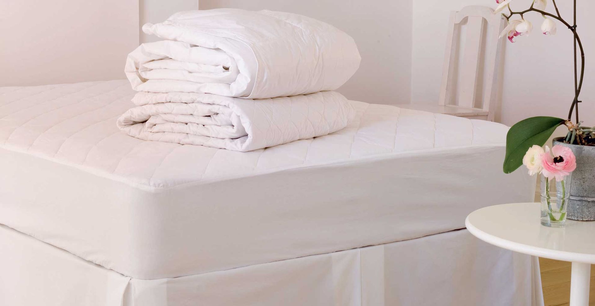 bed showing bedding piled on top on the mattress to support an article with expert advice to answer how often should you wash a mattress protector