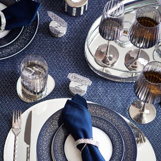 Dark blue table with silver and blue dinnerware and glasses