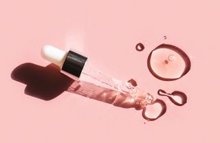 skincare pipette and liquid on pink background