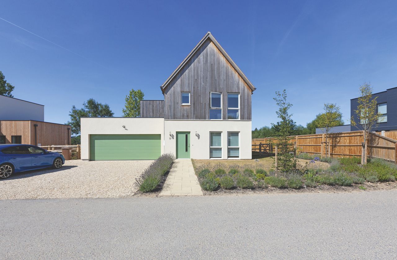 grey and white self build house with green garage door