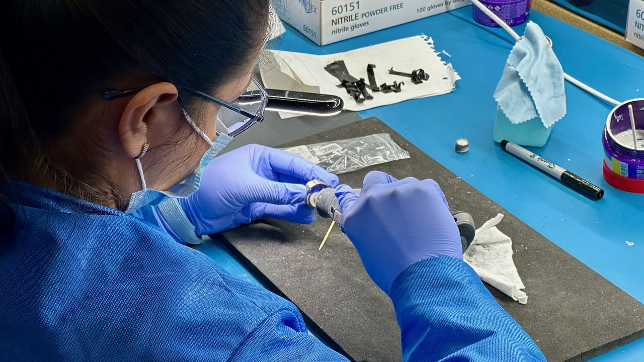An Ultrahuman factory worker polishes the excess resin off of a Ring Air unit.