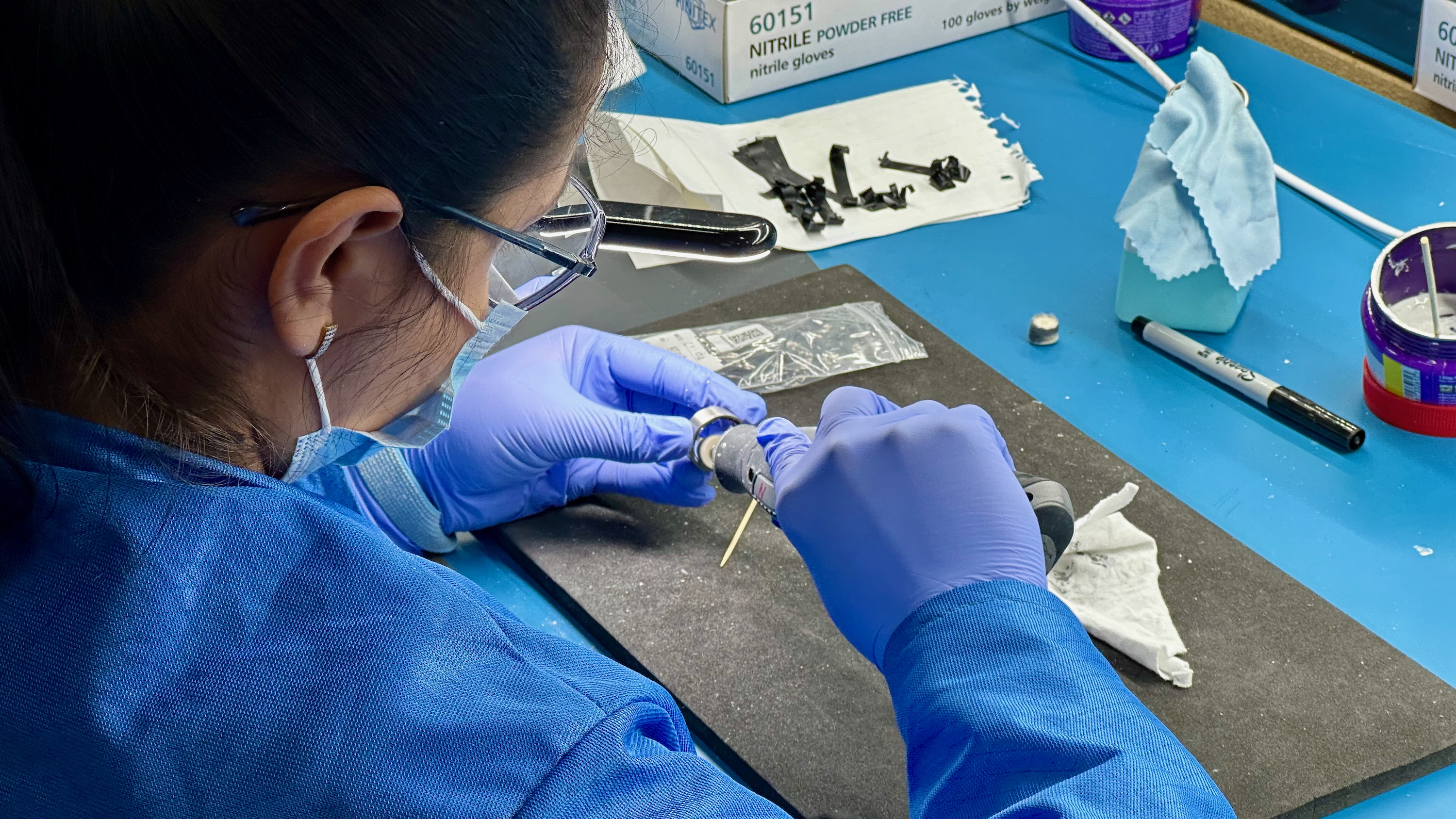 An Ultrahuman factory worker polishes the excess resin off of a Ring Air unit.