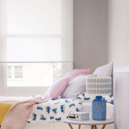 A bedroom with light pouring through a large window next to the bed