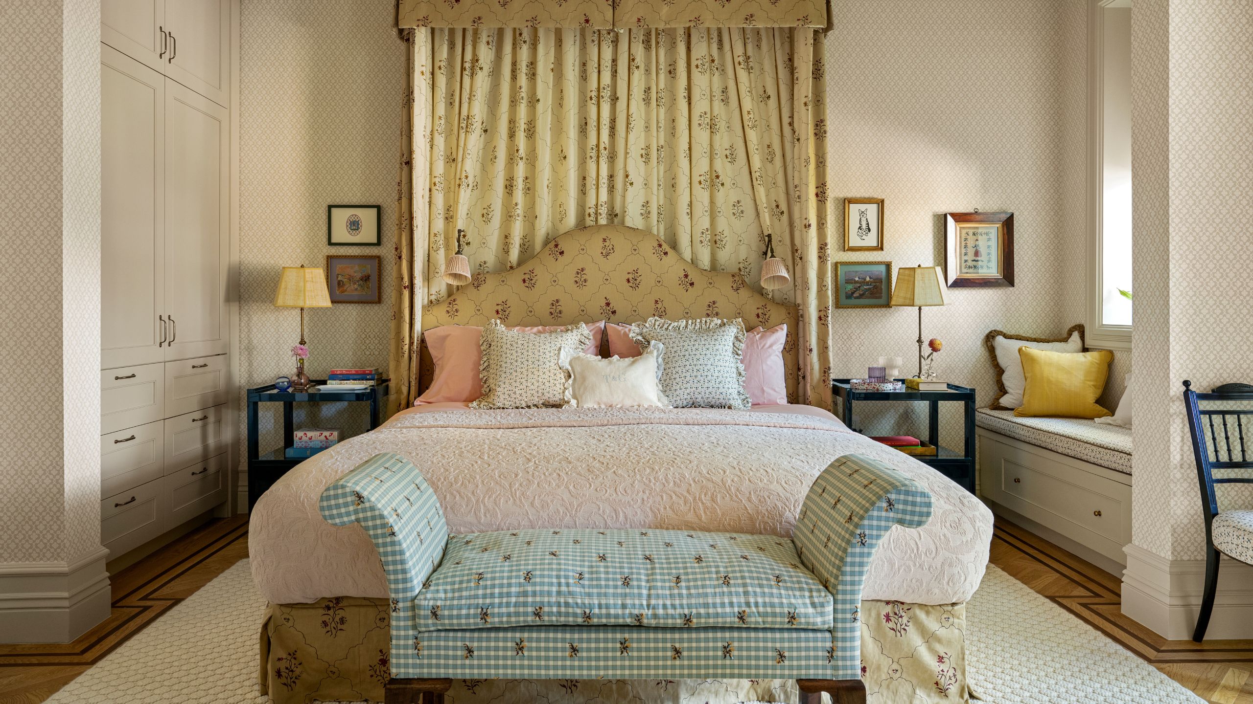 a traditional bedroom with a floral canopy bed and blue gingham end of bed bench