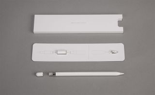 View of an Apple Pencil, a spare nib and the inner packaging from the box pictured against a grey background