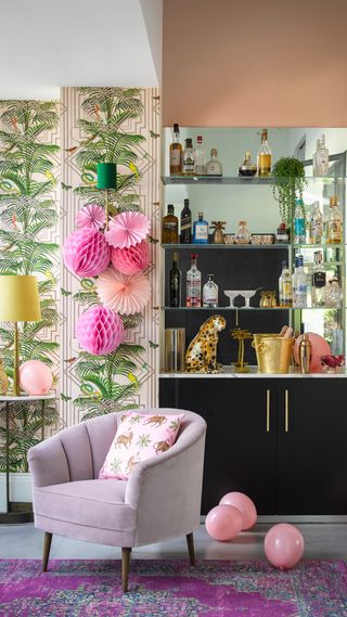 A living room with drinks cabinet, paper decorations, Pooky Monique Table lamp in brass, tapered shade in Buttercup velvet and bar cart