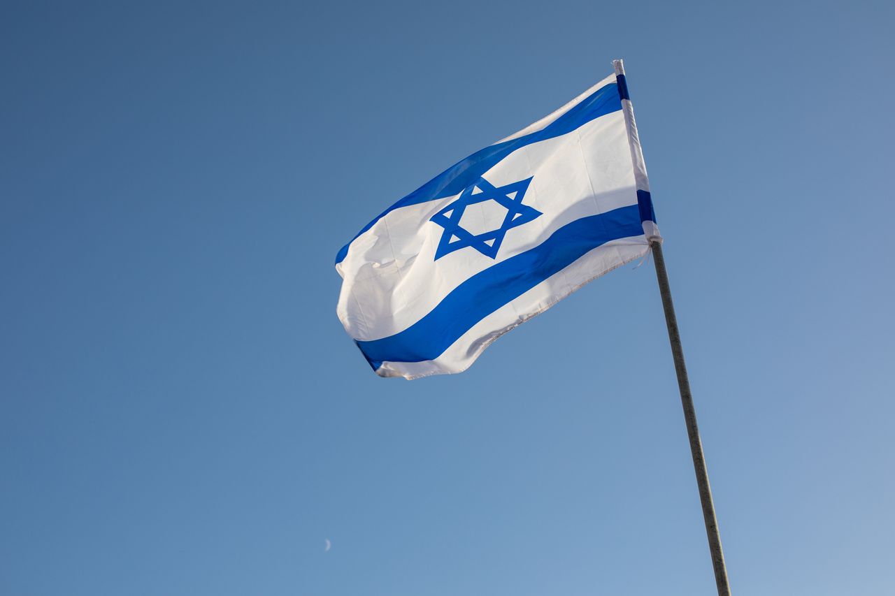 The flag of Israel flying with the moon behind in Jerusalem in Israel.