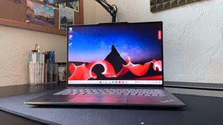 The Lenovo ThinkPad X1 2-in-1 Gen 9 sitting on a black desk with a pencil cup and pictures in the background