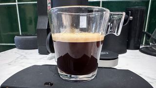 An espresso shot poured into an espresso glass on top of a coffee scale.