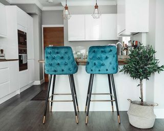 Small white modern kitchen with teal bar stools