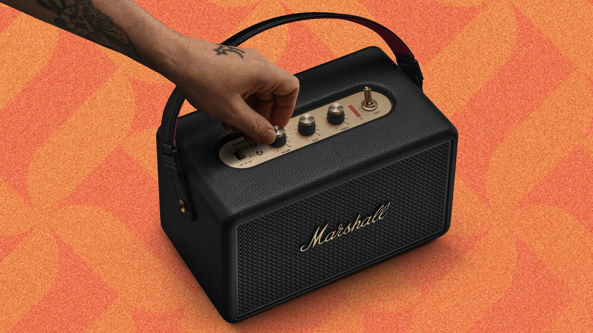 an image of the black Kilburn III speaker being switched on, against an orange patterned background