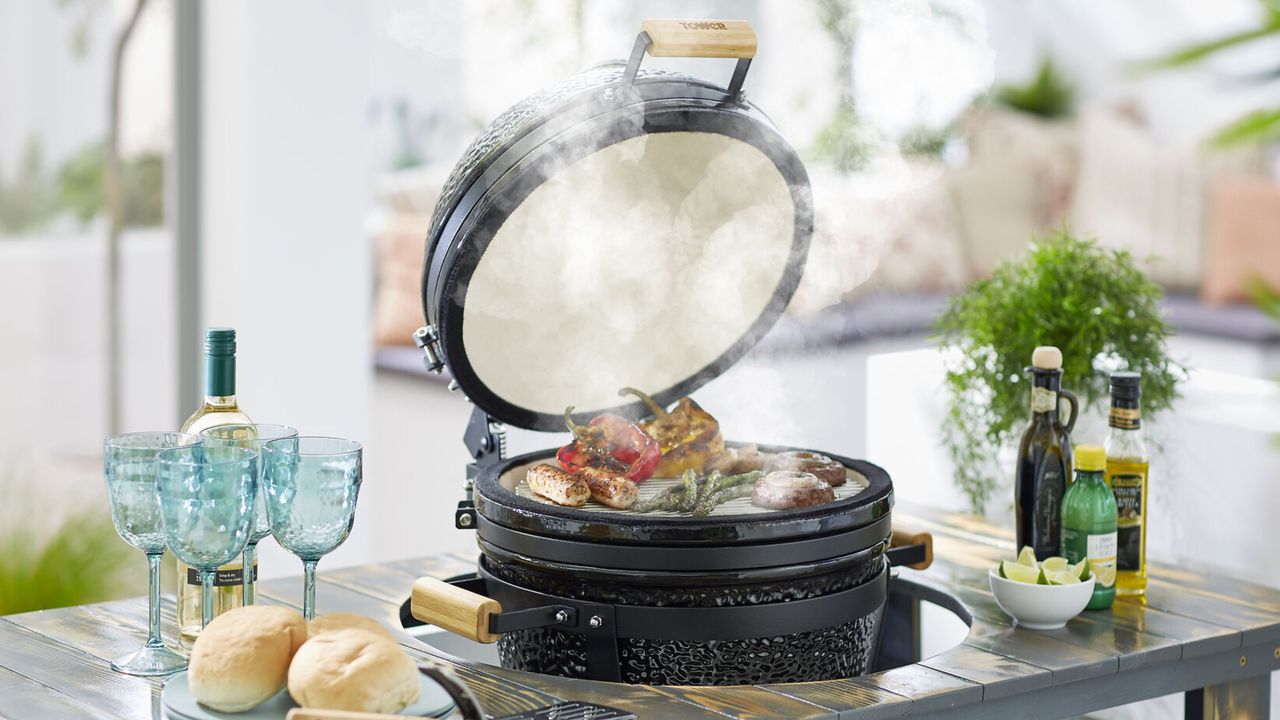 Tower Kamado Maxi Charcoal BBQ lifestyle image on a plate with food around and smoke coming out