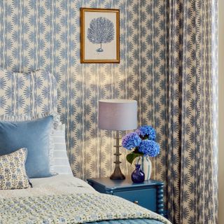 John Lewis table lamp on blue bobbin bedside table in wallpapered bedroom