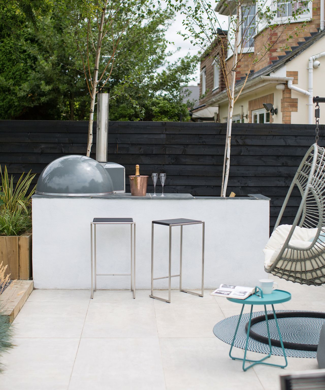 A white built in bar area with outdoor pizza oven and cooking facilities