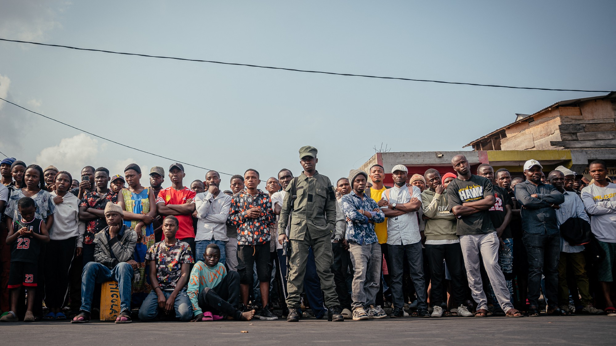 An AFC/M23 soldier stands guard with a Kalashnikov rifle in front of a crowd in Goma, DR Congo