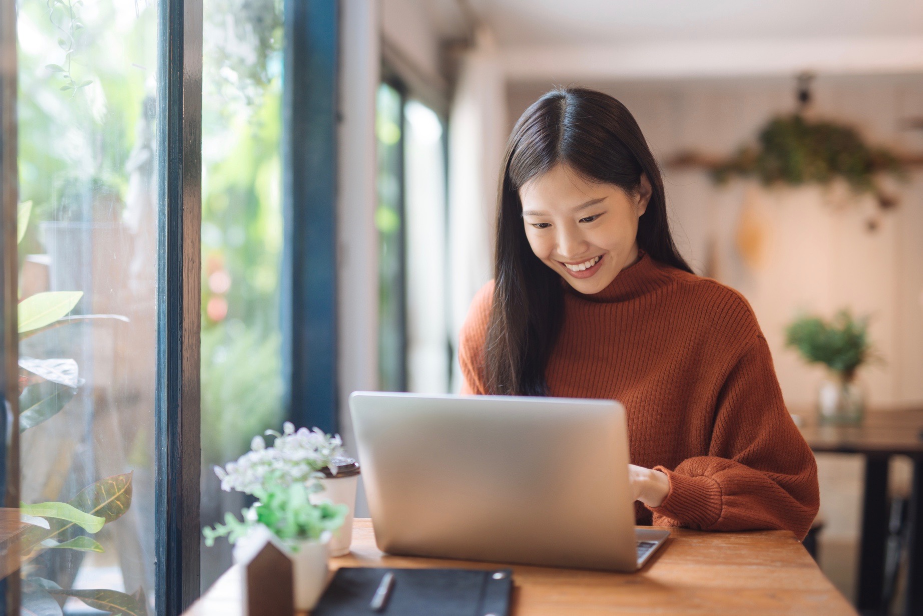 Young woman working at a coffee shop with a laptop