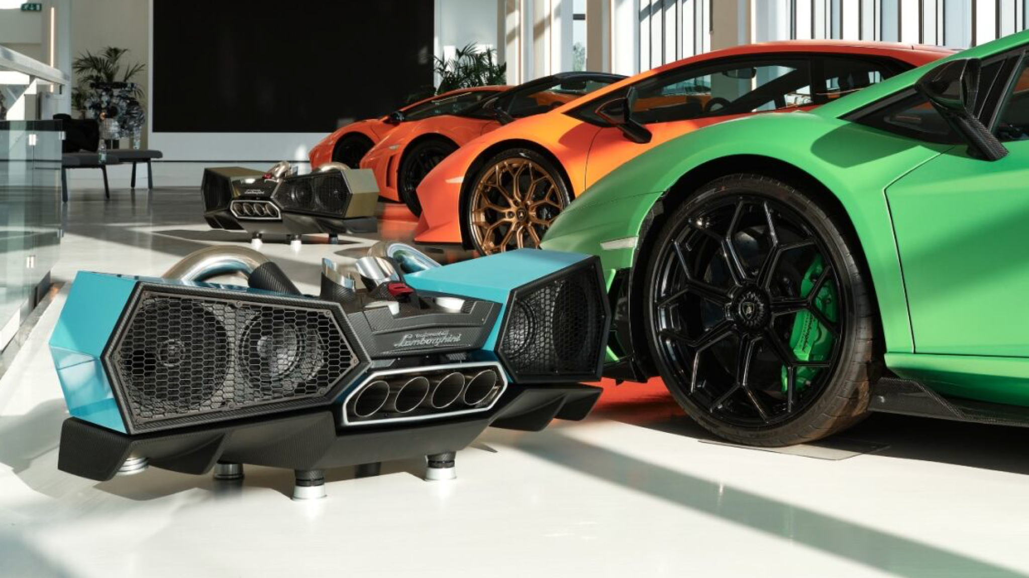 iXOOST ESAVOX speaker in a garage or showroom full of Lamborghini cars