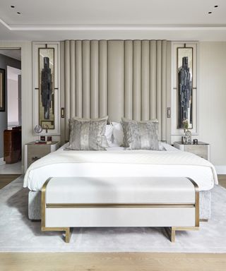 An example of bedroom storage ideas showing a neutral bedroom with statement headboard and wall sculptures either side of the bed