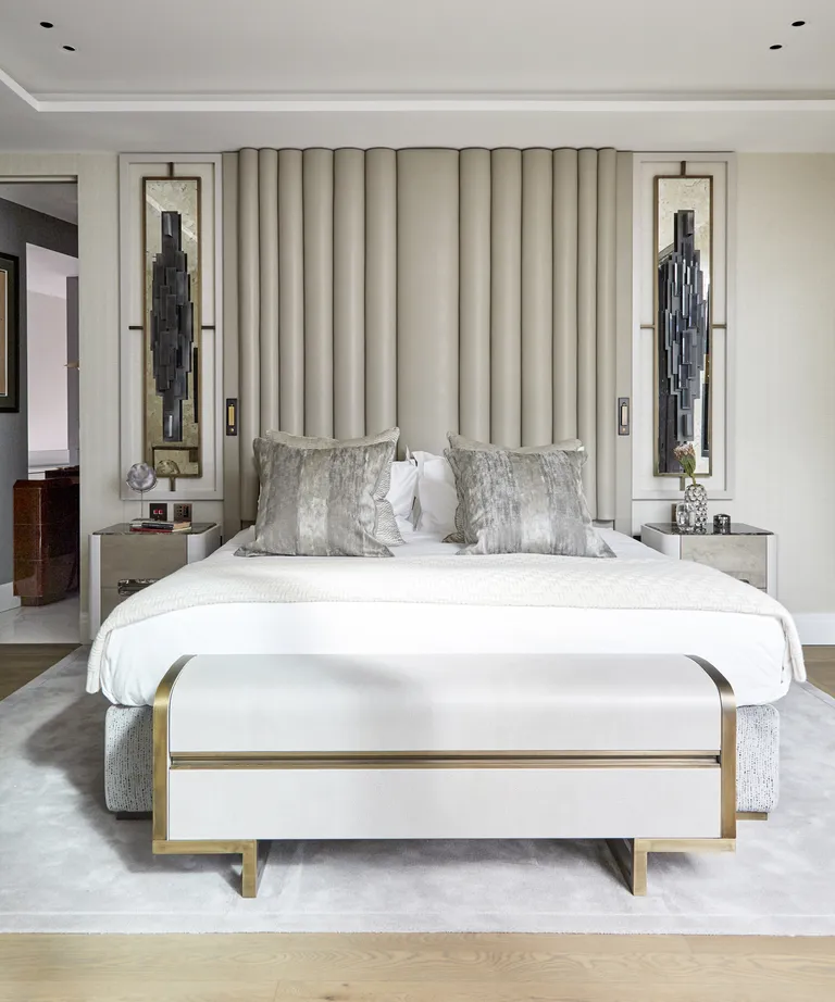 A neutral bedroom with statement headboard and wall sculptures either side of the bed