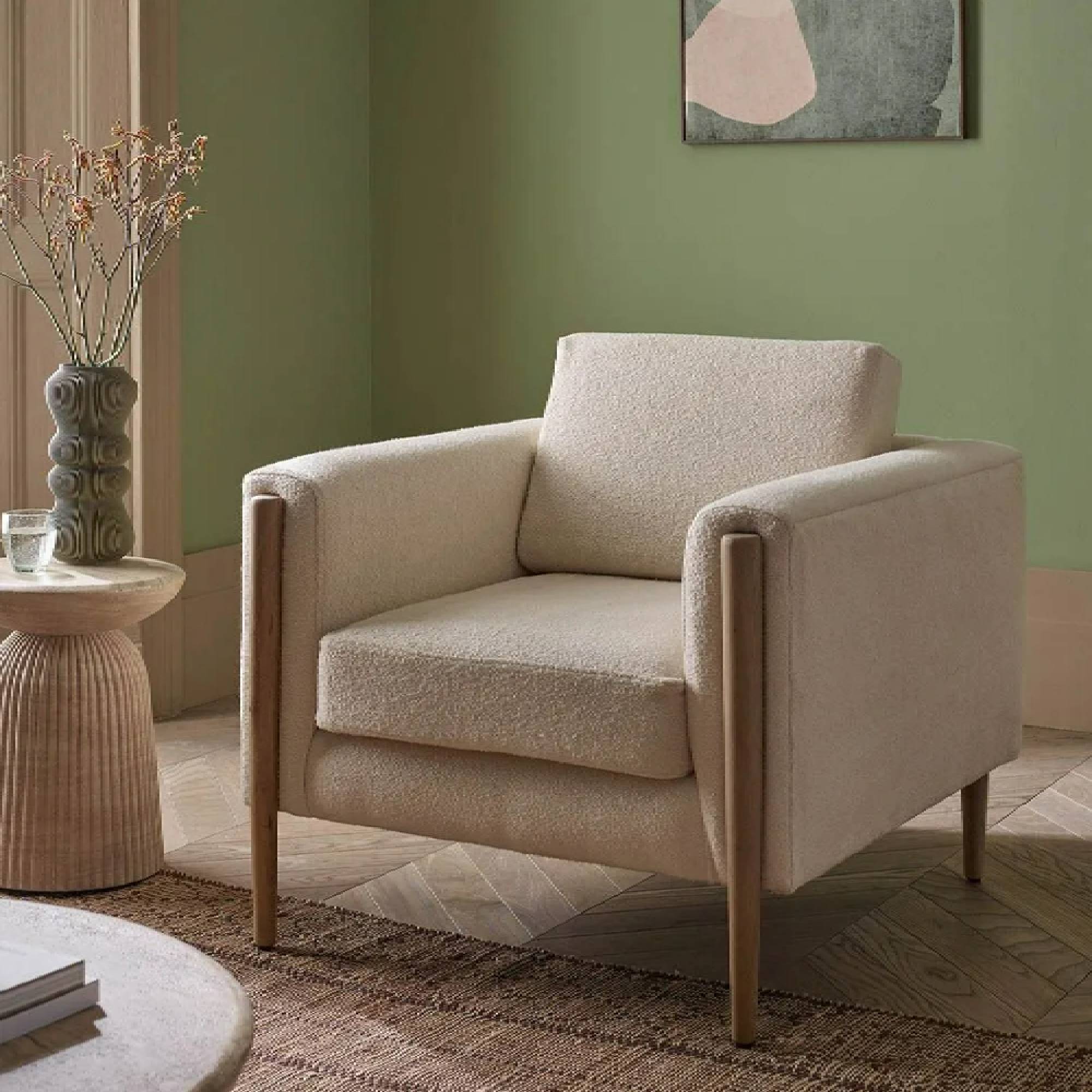 A cream, square, boucle armchair in an olive green lounge, from Atkin & Thyme.
