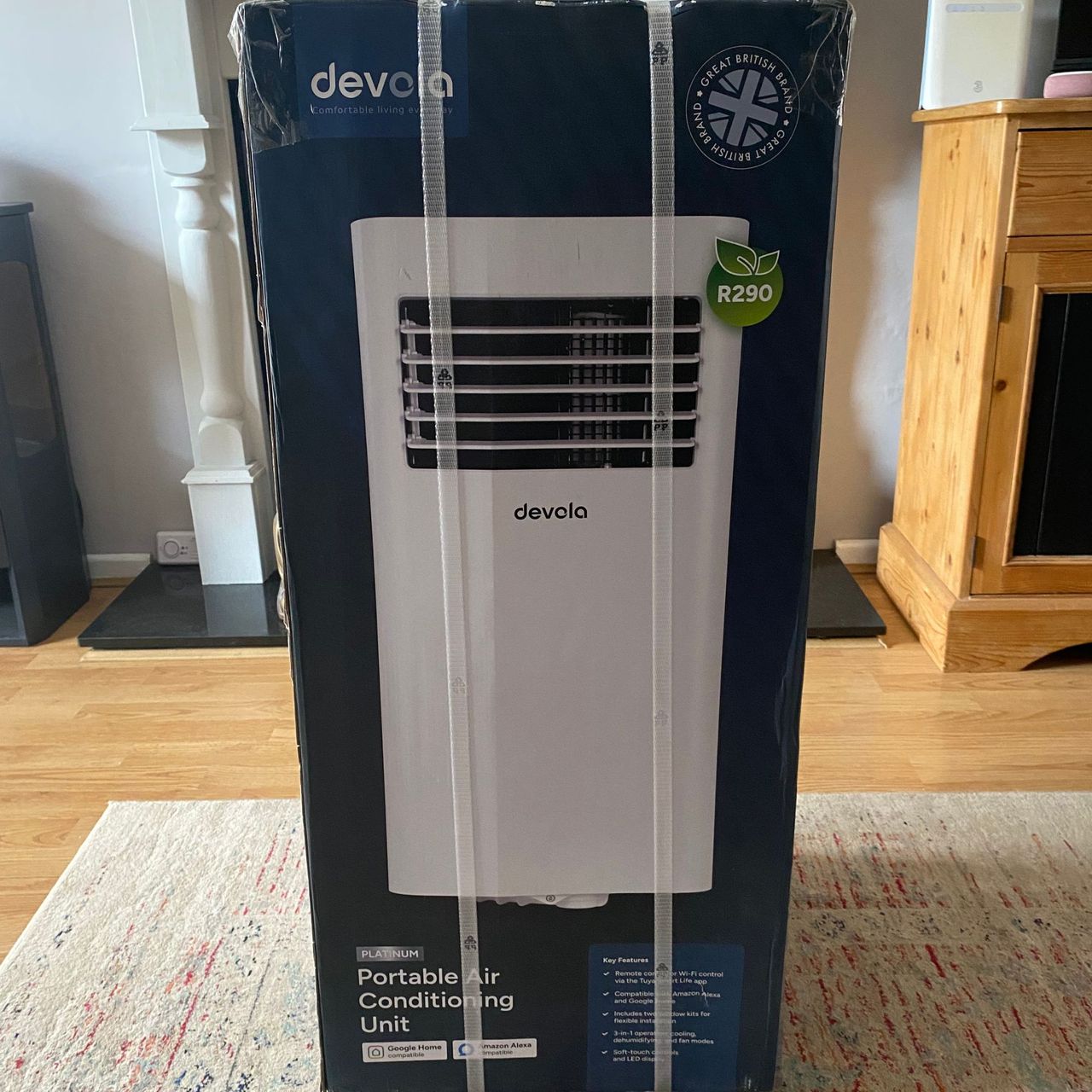 Packing of the Devola DVAC09CW portable air conditioner sitting on a rug in a neutral living room
