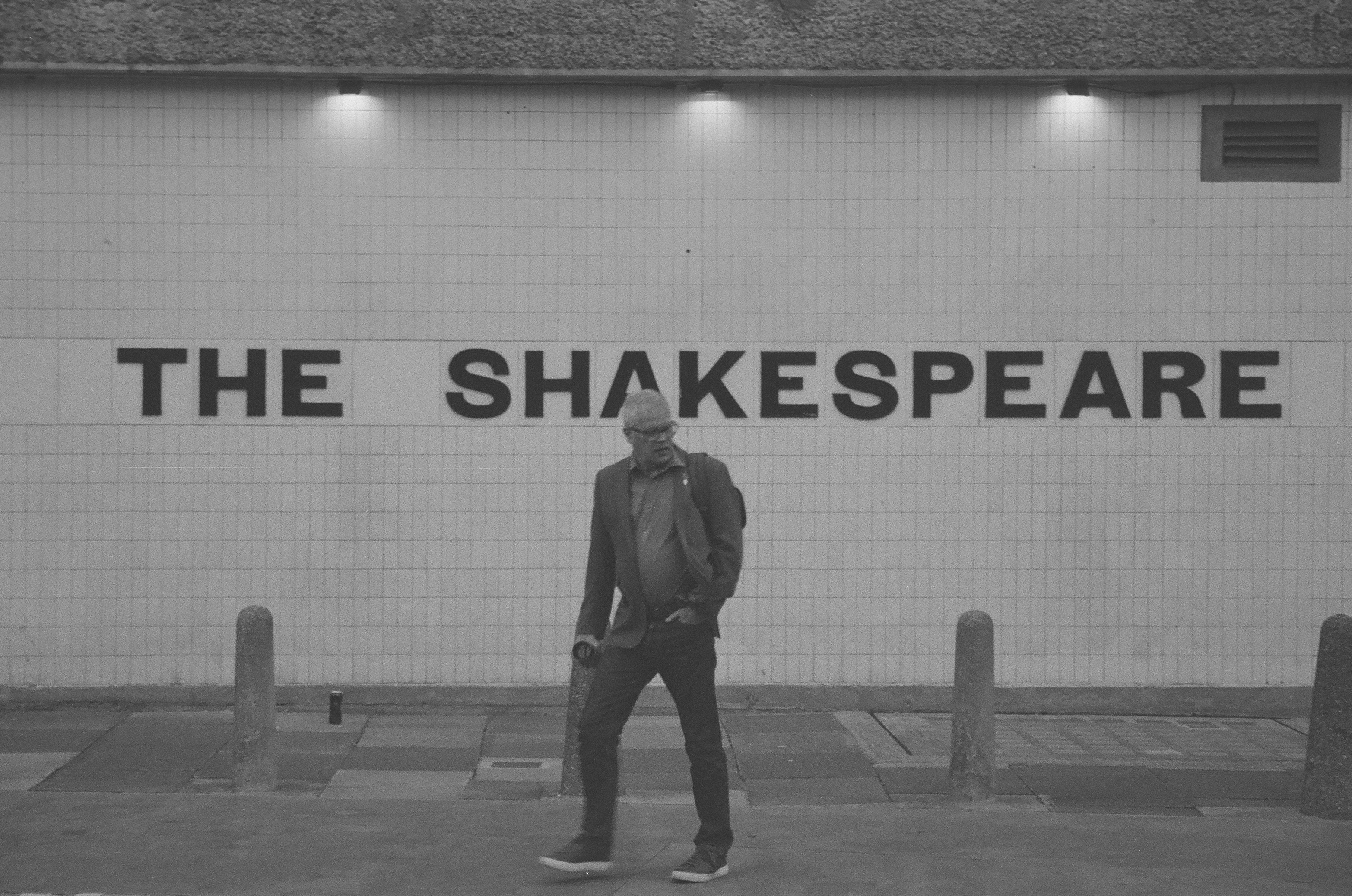 Sample photo of AgfaPhoto APX 400 35mm film showing a man walking in front of a sign reading &#039;The Shakespeare&#039;