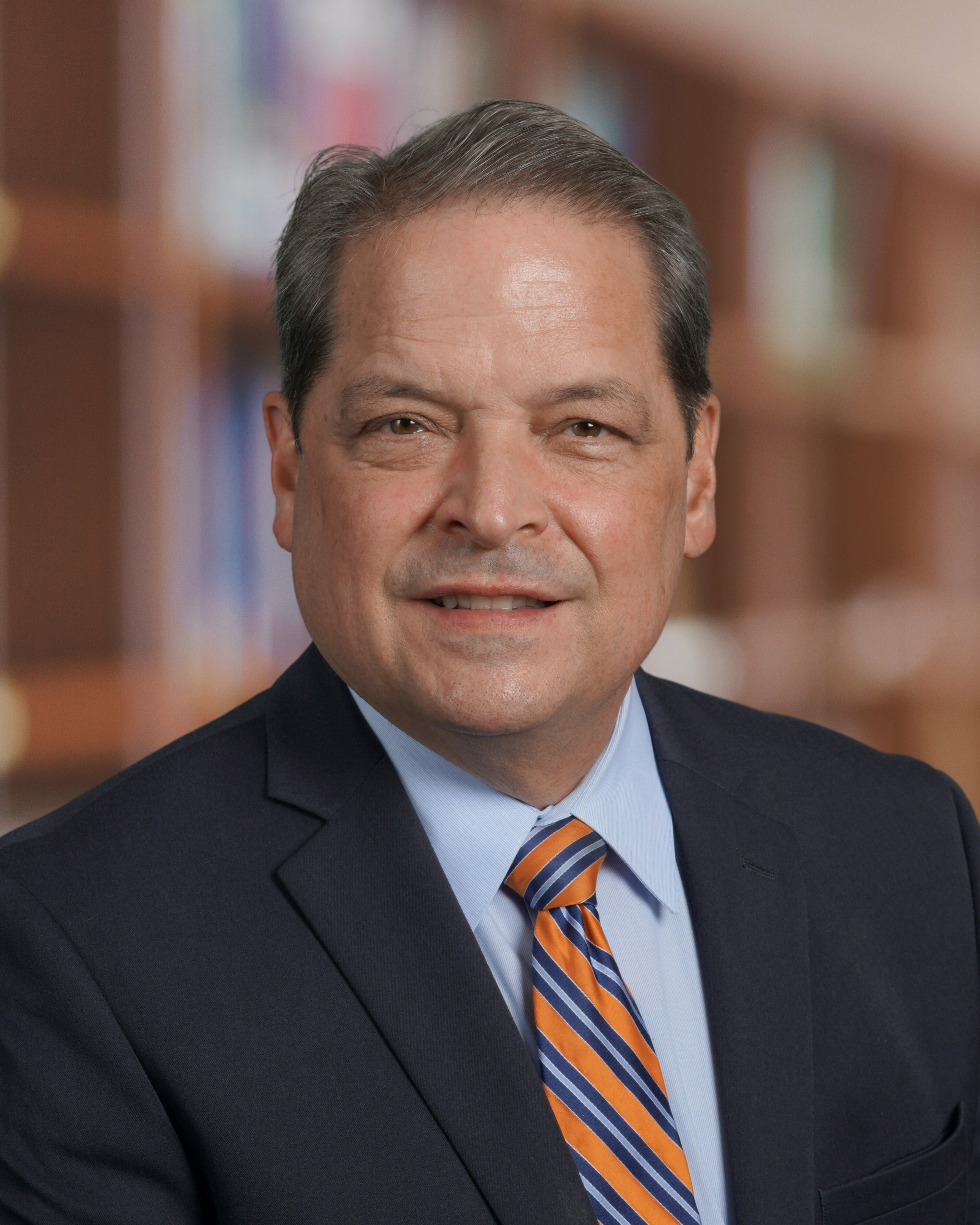 A headshot of James Batson wearing a suit and a tie.