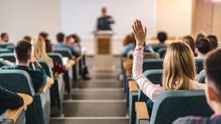 A woman raises her hand in a college lecture.