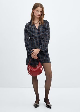 model wears wrap checked dress and holds a red handbag and wears pointed toe heels 