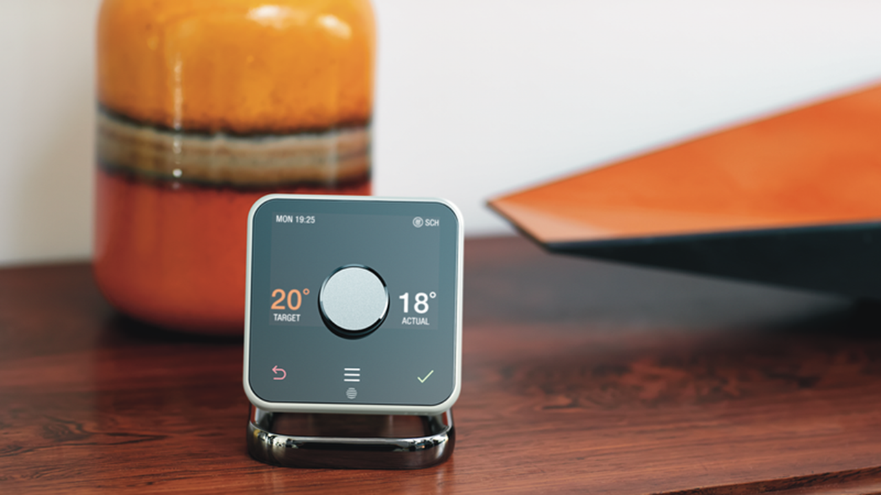 Hive Thermostat on dark wood furniture with glazed ceramic vase in background