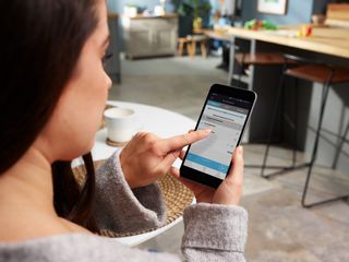 Woman using Beko HomeWhiz app with her autodose machine dishwasher