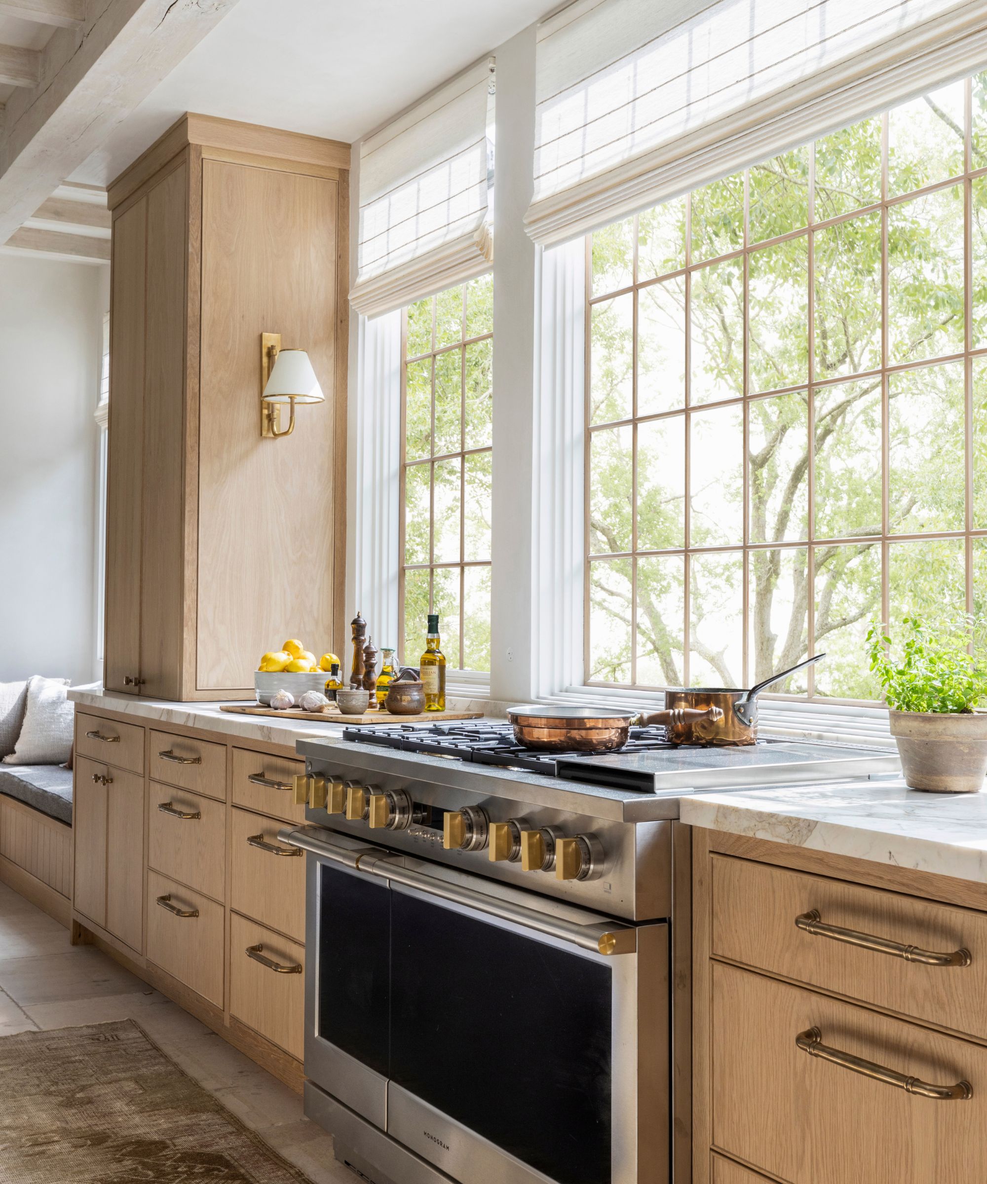 A wooden kitchen with marble countertops and windows where the backsplash would usually be
