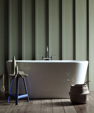 Green painted bathroom with bathtub, panelling on walls behind bathtub