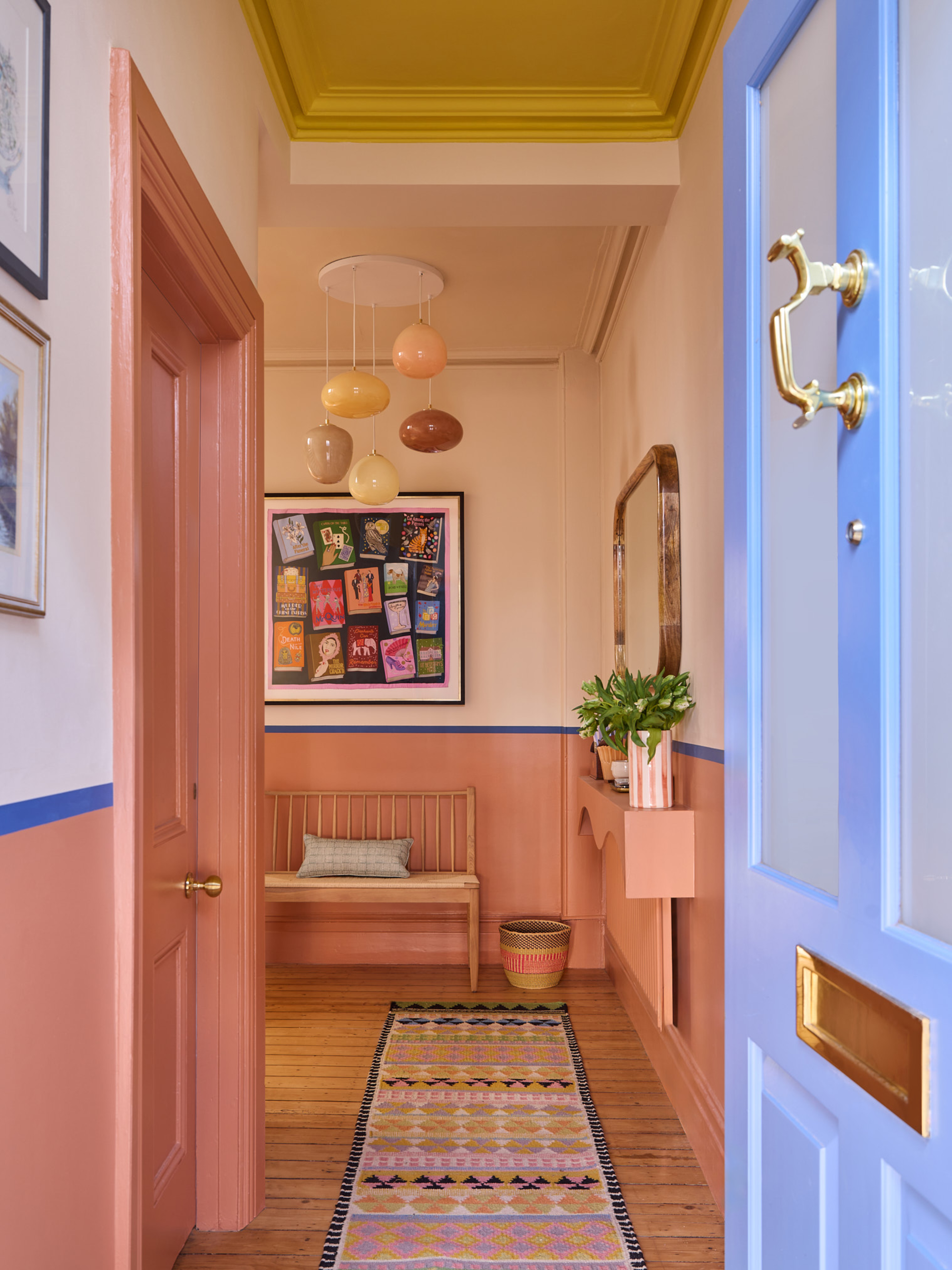 A view through an open front door into an entryway with pastel tones and a pastel pendant lighting fixture