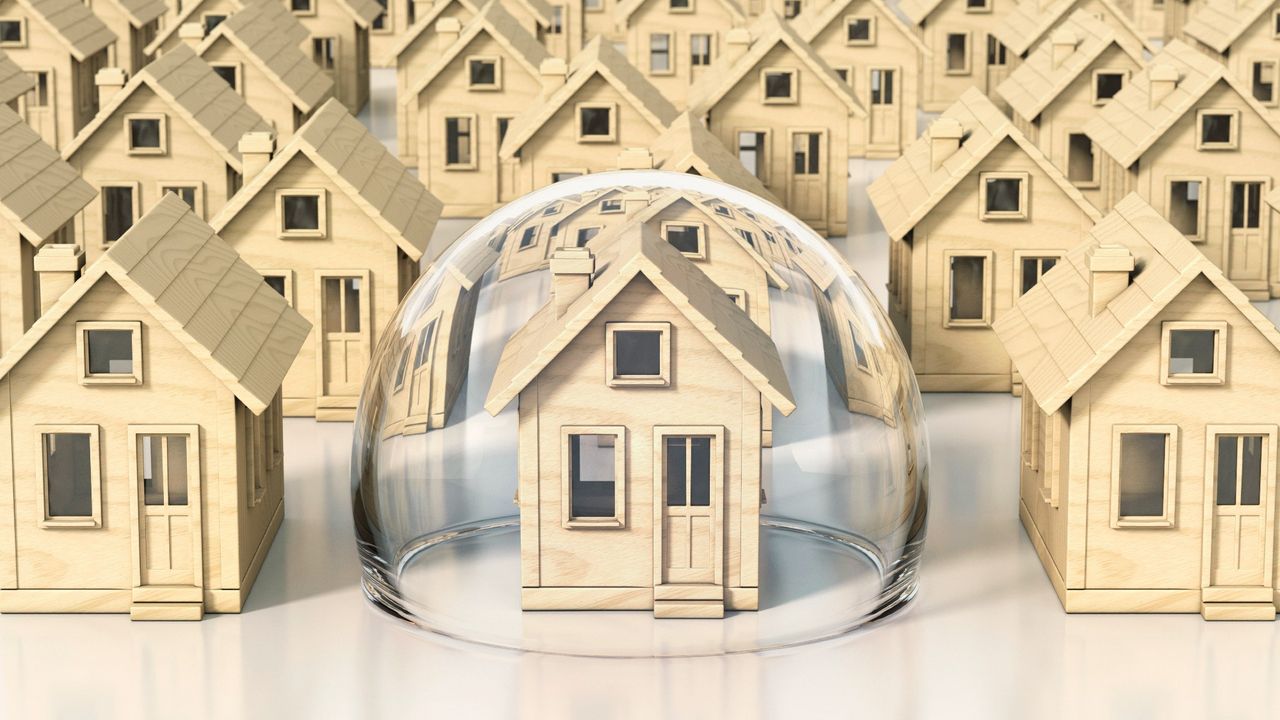 Field of identical wooden miniature houses, one under a protective glass dome