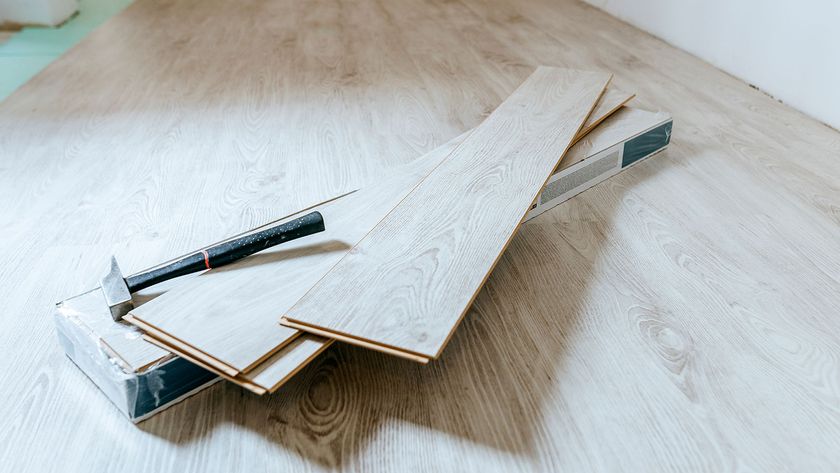 wood flooring being installed in a room with a pack of wooden planks in the middle of the room