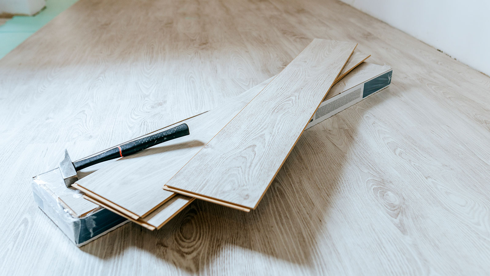 wood flooring being installed in a room with a pack of wooden planks in the middle of the room