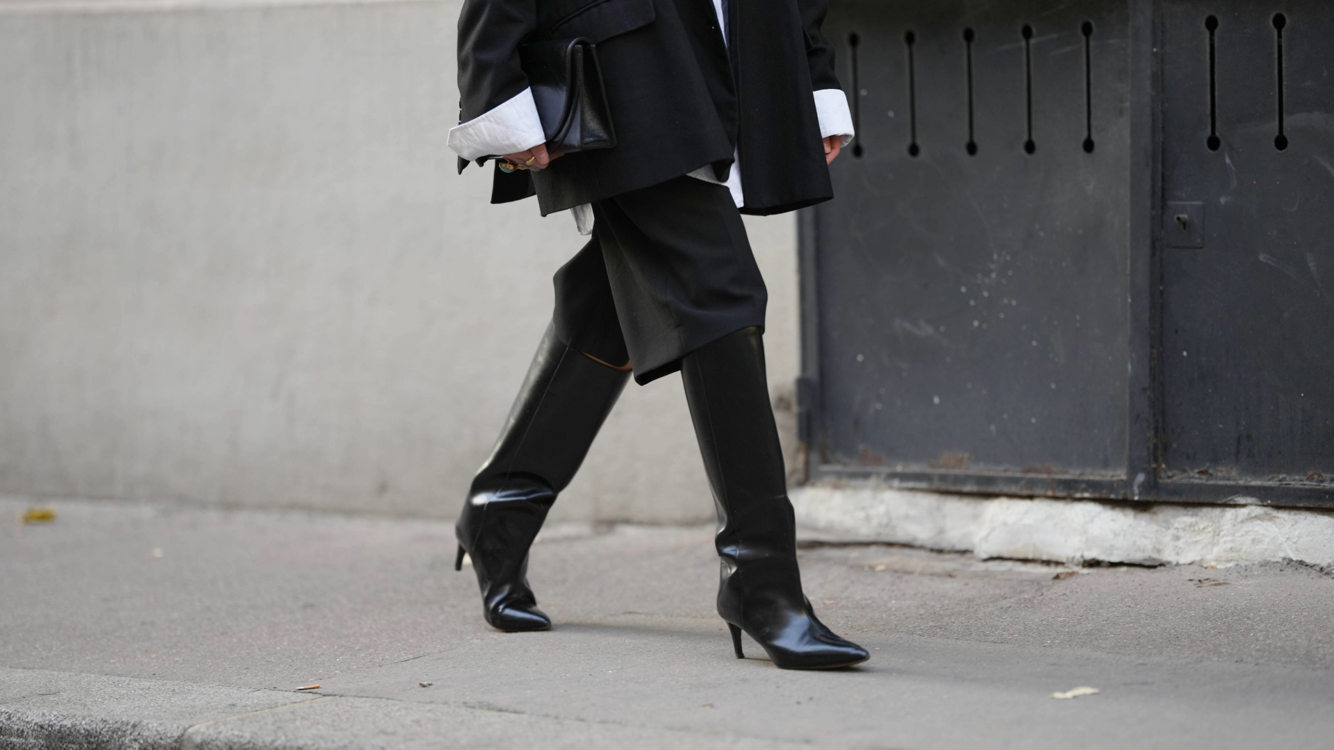 PARIS, FRANCE - NOVEMBER 05: Emy Venturini wears a black oversized blazer jacket by The Frankie Shop layered over a white cotton shirt by Louis Vuitton, black tailored knee-length shorts by Zara, black leather heeled boots by Toteme, a vintage black leather clutch bag, during a street style fashion photo session, on November 05, 2025 in Paris, France. (Photo by Edward Berthelot/Getty Images)